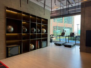 A modern gym with treadmills, a large window, and a wall with exercise equipment.