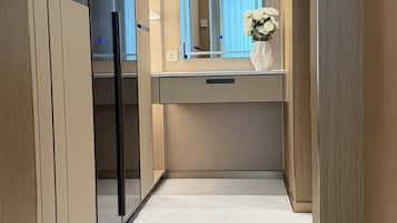 A modern bathroom with a marble floor, a large mirror, and a vase with flowers on the vanity.