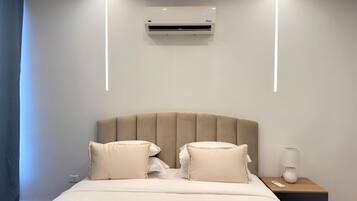 Een hotelkamer met een bed, nachtkastje, lamp en een airconditioning.