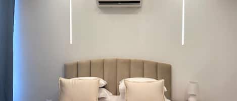 Een hotelkamer met een bed, nachtkastje, lamp en een airconditioning.