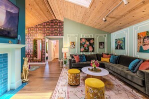 A living room with a fireplace, a sofa set, a coffee table, and a patterned rug. - The Gilded Bungalow • Walk to Town Green • Hot Tub • Firepit • Pink Kitchen (Windsor)