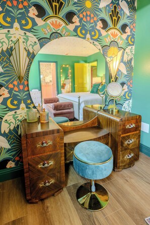 A room with a bed, a vanity with a mirror, and a stool. - The Gilded Bungalow • Walk to Town Green • Hot Tub • Firepit • Pink Kitchen (Windsor)