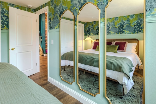Un dormitorio con cama, espejo y puerta.