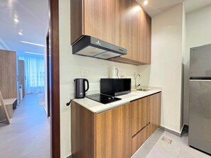 Eine moderne Küche mit Holzschränken, einer eingebauten Mikrowelle, einem Wasserkocher und einem Edelstahl-Kühlschrank.