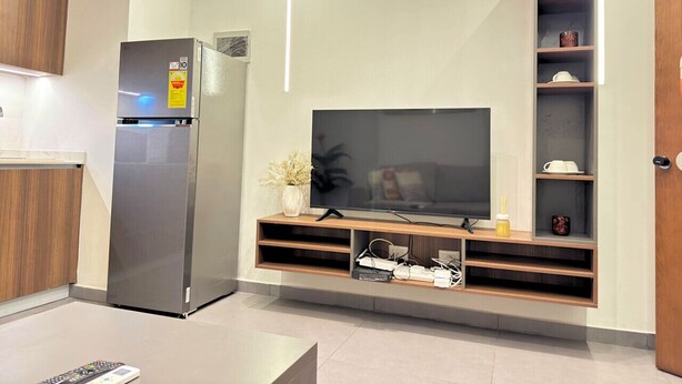 A modern kitchen with a built-in refrigerator, a flat-screen TV, and wooden cabinetry.