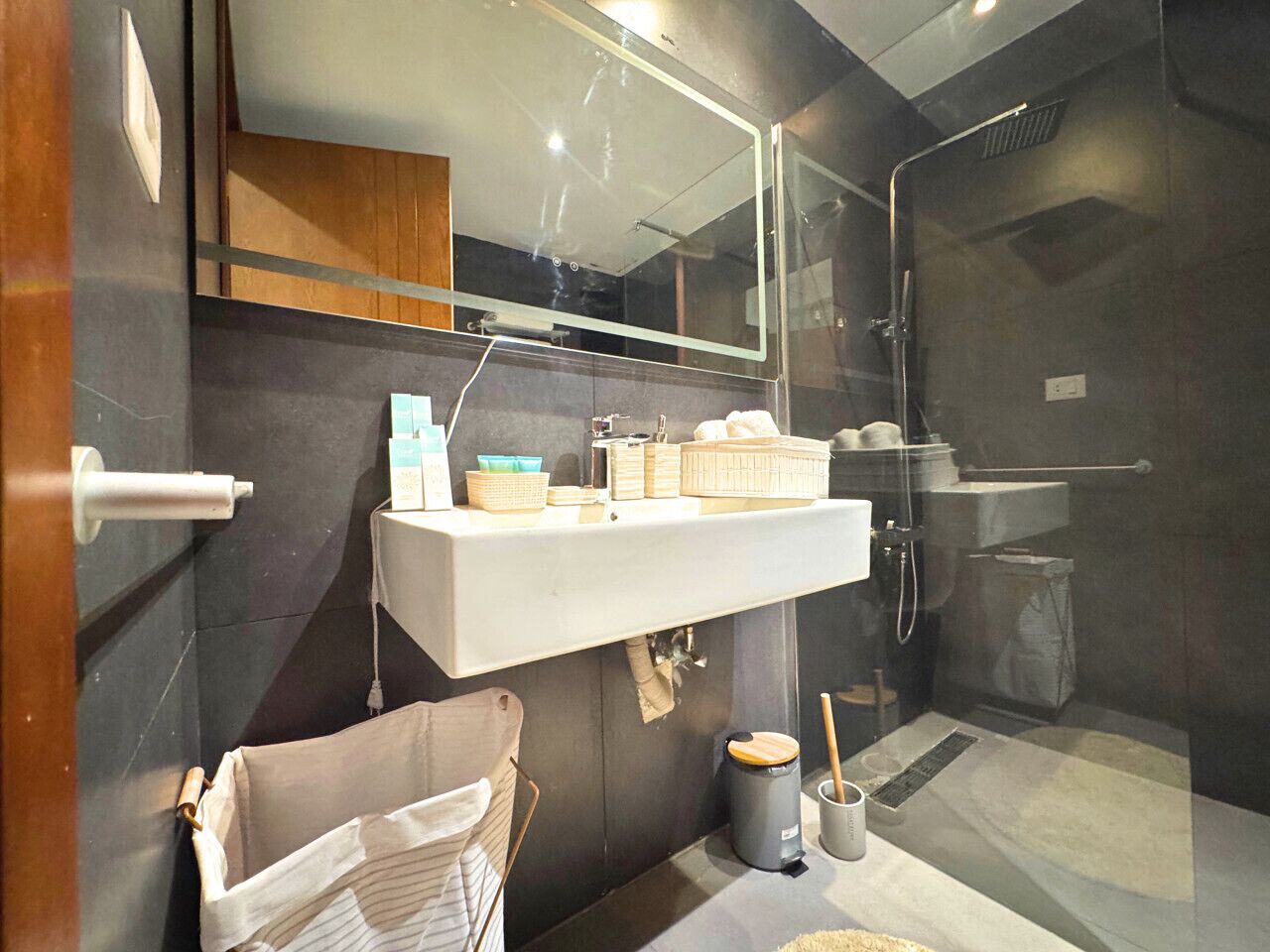Une salle de bain moderne avec une douche à parois de verre, un lavabo blanc avec espace de rangement et un porte-serviettes.