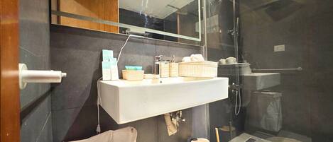 Une salle de bain moderne avec une douche à parois de verre, un lavabo blanc avec espace de rangement et un porte-serviettes.