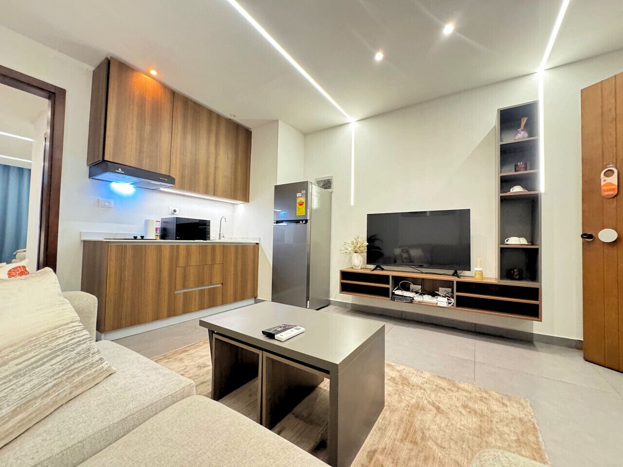 Een moderne woonkamer met een bank, salontafel, televisie en een inbouwkeuken.
