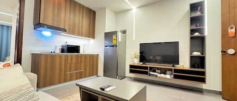 Een moderne woonkamer met een bank, salontafel, televisie en een inbouwkeuken.