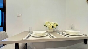 A dining table set with plates, glasses, and a vase of flowers.