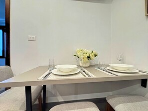 A dining table set with plates, glasses, and a vase of flowers.