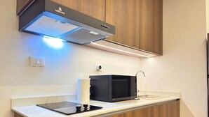 A compact kitchen with a microwave, a built-in oven, and a modern faucet.