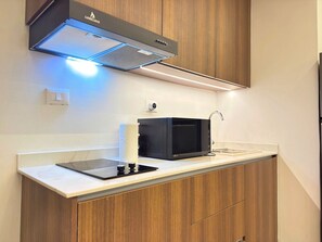 A compact kitchen with a microwave, a built-in oven, and a modern faucet.