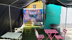 A tent with a mural, artificial grass, and outdoor furniture. - Green Little Havana (Miami)