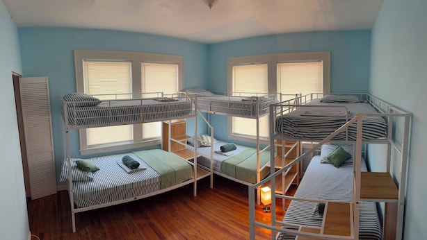 A bunk bed room with a wooden floor, a window with blinds, and a door. - Green Little Havana (Miami)
