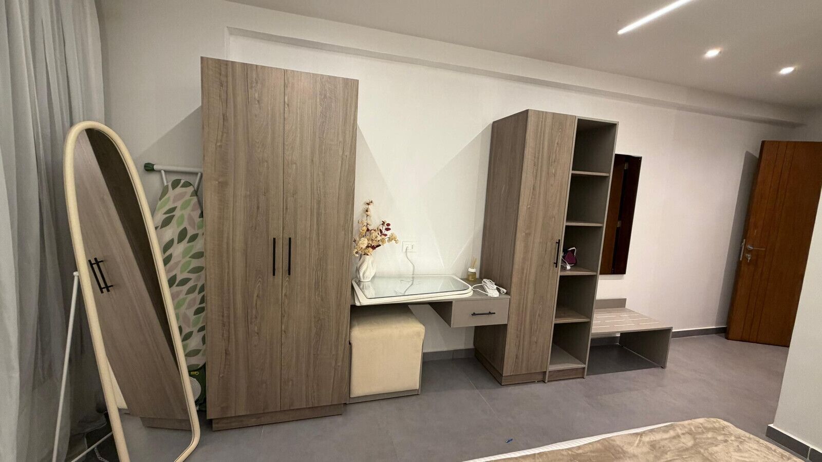 Een slaapkamer met een bed, een kledingkast, een bureau en een spiegel.