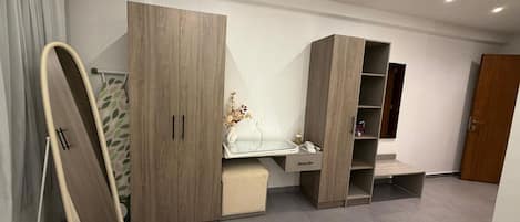 Een slaapkamer met een bed, een kledingkast, een bureau en een spiegel.