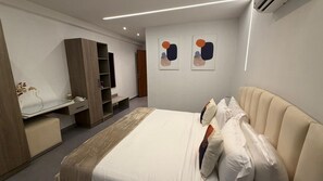 A modern hotel room with a bed, a desk, and a wardrobe. - Cozy 1 bedroom Studio Apartment with Pool in Gombe (Kinshasa)