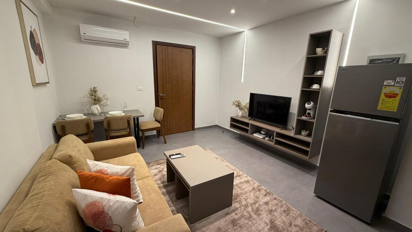 Ein modernes Wohnzimmer mit Sofa, Couchtisch, Fernseher und Einbauschränken.
