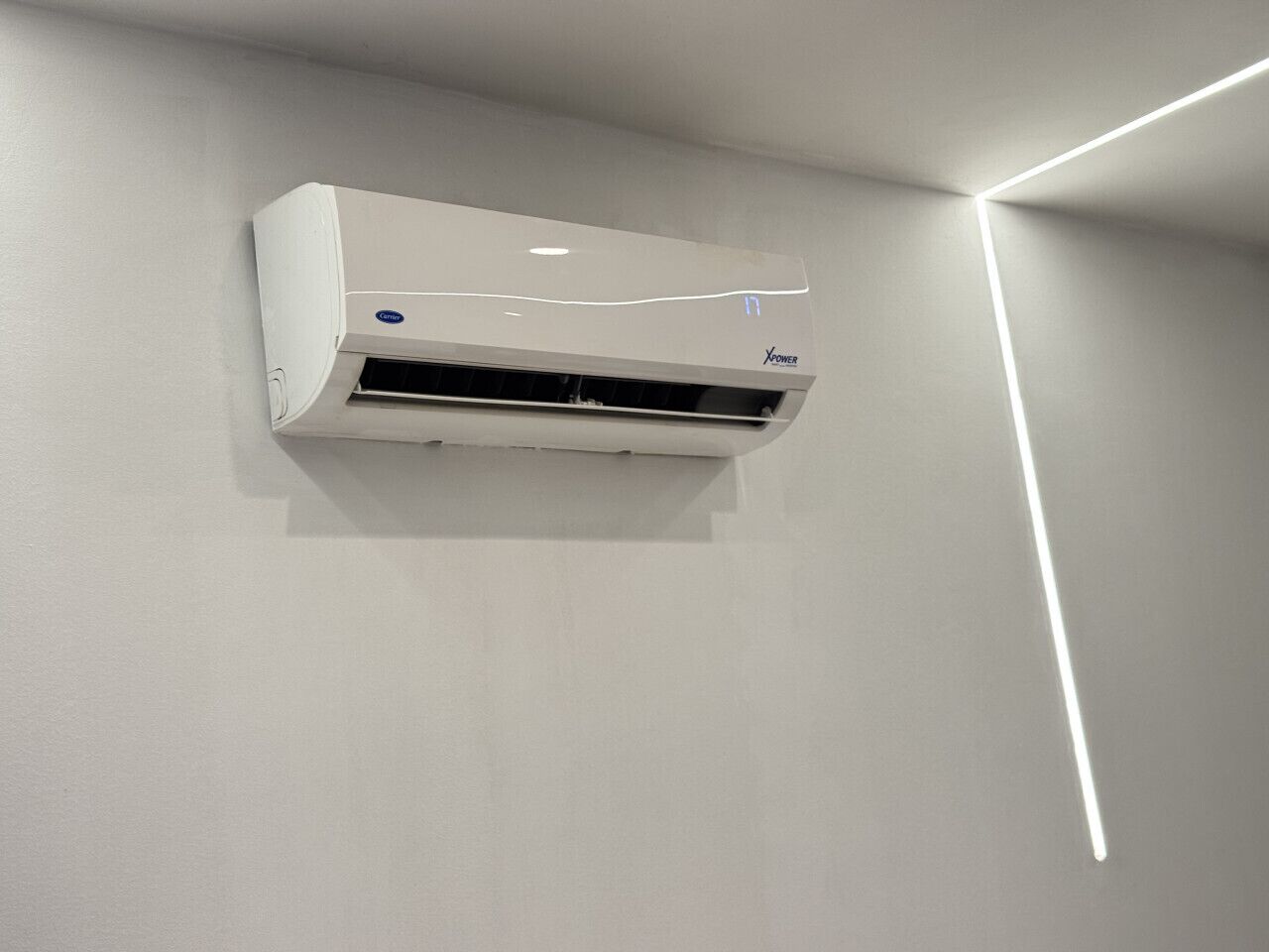 Un equipo de aire acondicionado blanco montado en una pared lisa con una lámpara moderna.