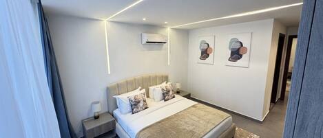 Een moderne hotelkamer met een bed, nachtkastje, lamp en kunstwerk aan de muur.