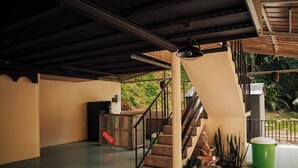 A spacious indoor area with a staircase, a Coca-Cola refrigerator, and a trash bin. - Naranjito River Retreat | Events & Groups | Sleeps 13 (Naranjito)