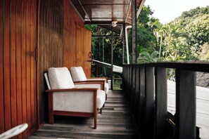 A wooden deck with two chairs and a railing overlooking a lush garden.