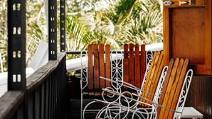 A covered outdoor seating area with wooden chairs and a table, overlooking a garden. - Naranjito River Retreat | Events & Groups | Sleeps 13 (Naranjito)