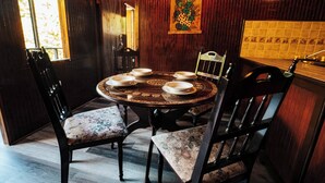A dining area with a round table set for four, surrounded by chairs with floral upholstery. - Naranjito River Retreat | Events & Groups | Sleeps 13 (Naranjito)