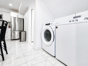 A modern kitchen with a stainless steel refrigerator, a washing machine, and a black chair. - Spacious and Bright 3-Bedroom Basement Unit in Thornhill (Markham)
