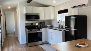 Una cocina moderna con armarios blancos, electrodomésticos de acero inoxidable y una mesa de comedor de madera.