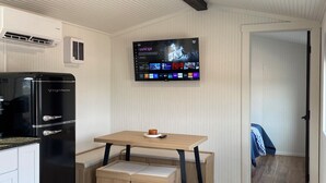 Una cocina moderna con refrigerador integrado, una mesa de comedor de madera con banco, y un televisor de pantalla plana montado en la pared.