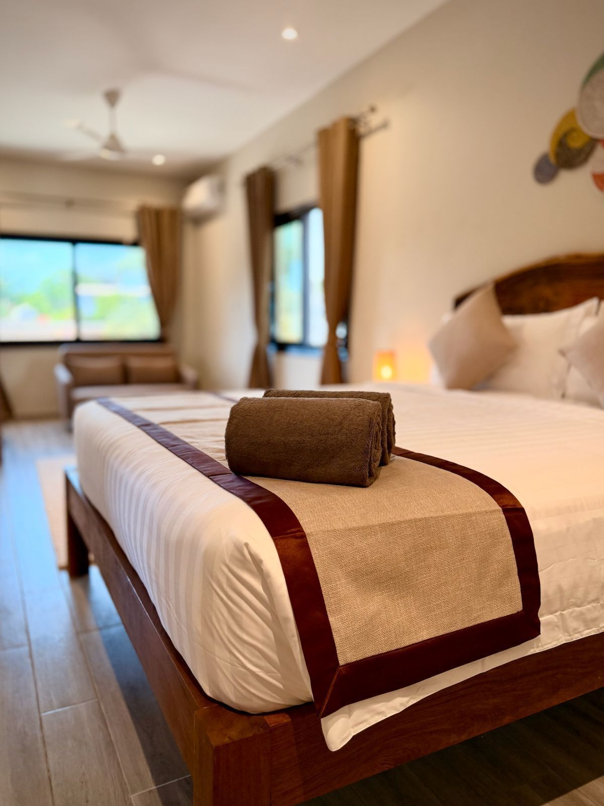 A hotel room with a large bed, a wooden headboard, and a view of the outdoors.
