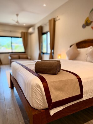 A hotel room with a large bed, a wooden headboard, and a view of the outdoors. - Teranga Tides (Bijilo)
