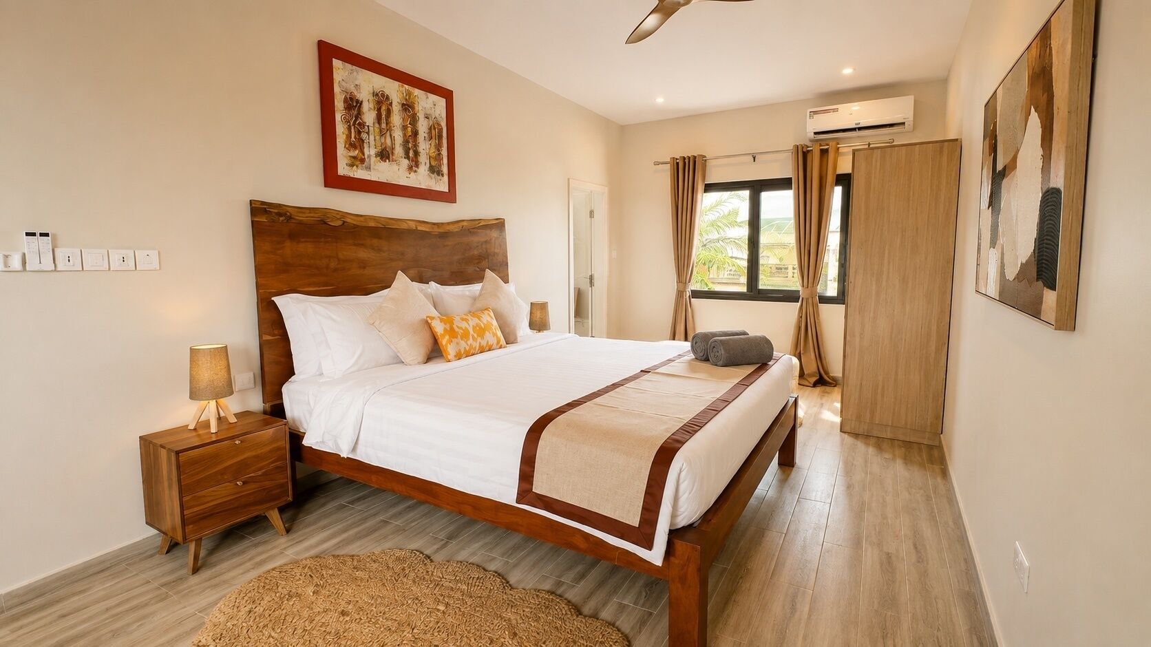 A bedroom with a wooden bed, bedside tables, a ceiling fan, and artwork on the walls.