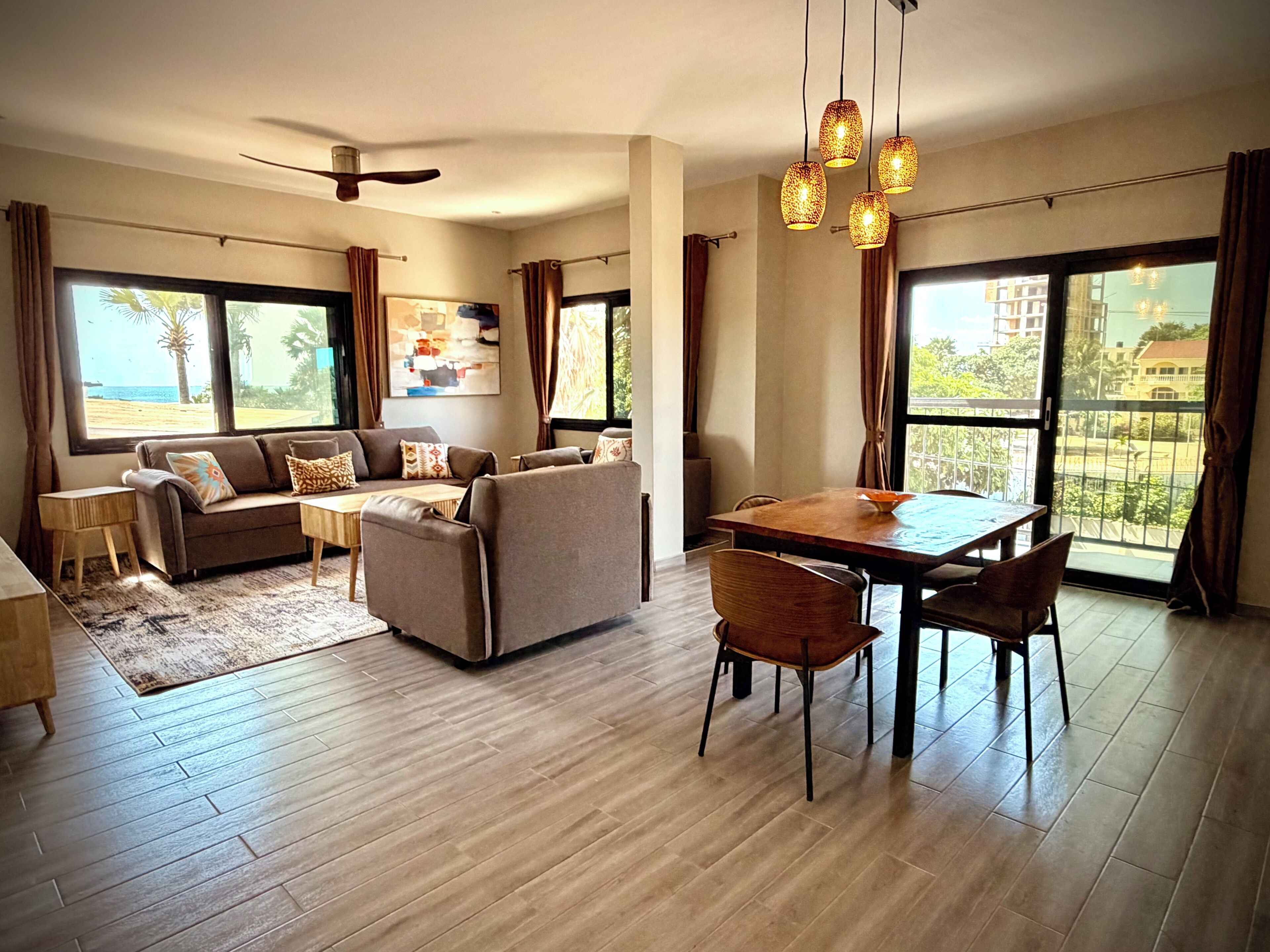 A spacious living area with a sofa set, dining table, and chairs.