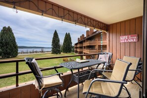 Eine Holzterrasse mit Sitzgelegenheit, Blick auf einen See und ein Schild mit der Aufschrift 'Das Leben ist besser am See'.