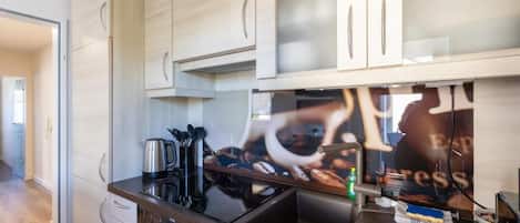 A modern kitchen with stainless steel appliances, wooden cabinets, and a large window.