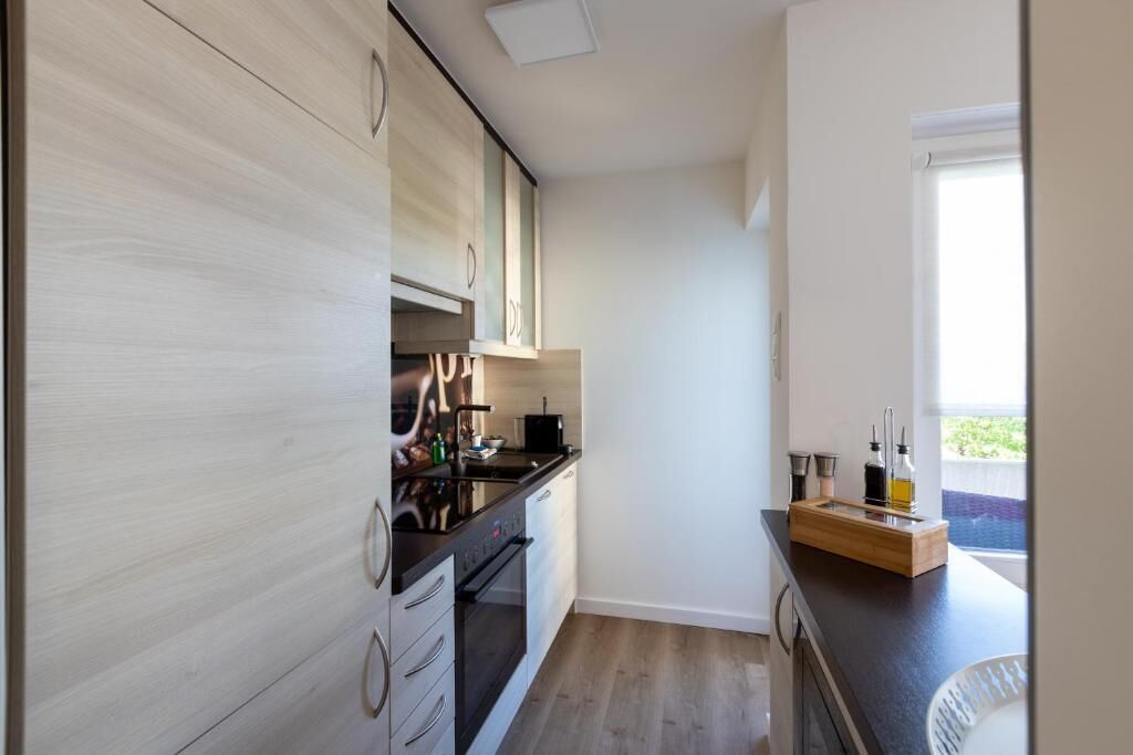 Una cocina moderna con encimera negra, armarios de madera y una ventana con vistas.