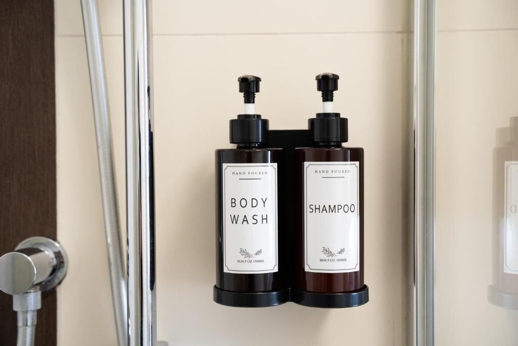 Two bottles of body wash and shampoo mounted on a wall.