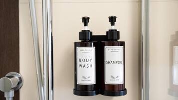 Two bottles of body wash and shampoo mounted on a wall.