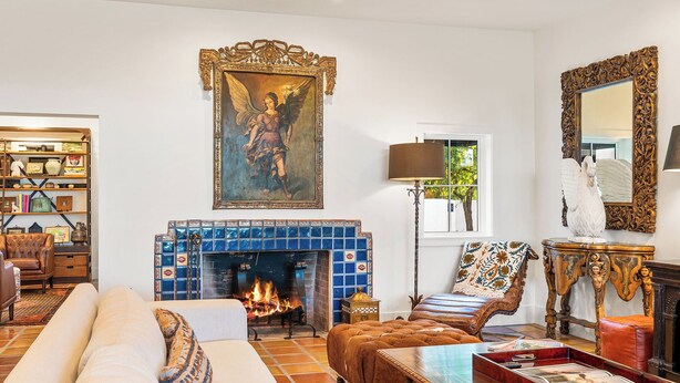 A living room with a fireplace, a sofa, a coffee table, and a bookshelf. - Desert Dreams Ranch - Idyllic 6 BR Next to the Polo Grounds (Indio)