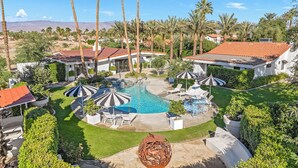A residential area with a swimming pool, lounge chairs, and palm trees. - Desert Dreams Ranch - Idyllic 6 BR Next to the Polo Grounds (Indio)