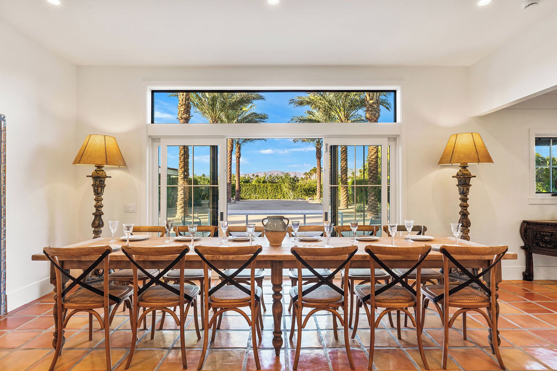 A dining area with a large table, chairs, and two lamps.