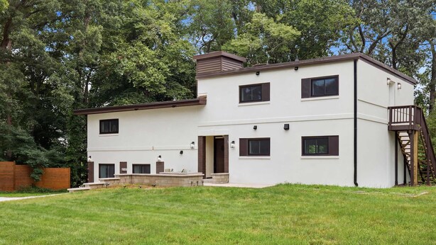 A modern two-story house with a flat roof, a front porch, and a staircase leading to a balcony. - Family-Friendly Suite - Springfield METRO (Springfield)
