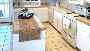 A modern kitchen with white cabinetry, a central island, a microwave, and a stove.