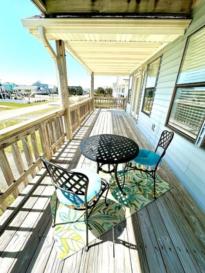 A wooden deck with a table and chairs, overlooking a residential area. - West end, great views, steps to beach, new rental! (Oak Island)