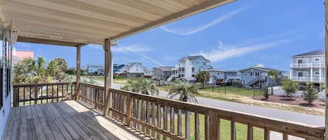 A wooden deck with a railing overlooking a residential street.