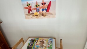 A small wooden table with a magazine and a book on it, placed against a wall with a framed picture above.