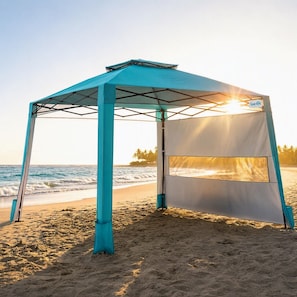 A beach tent with a view of the ocean and palm trees in the background.